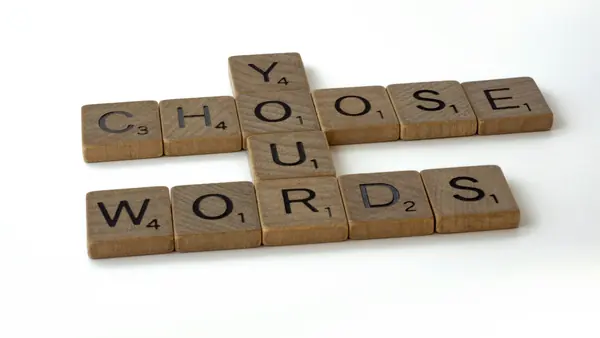 Wooden letter tiles spelling CHOOSE YOUR WORDS in a crossword layout